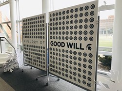 board that says Good Will with paper ornaments hanging on it. 