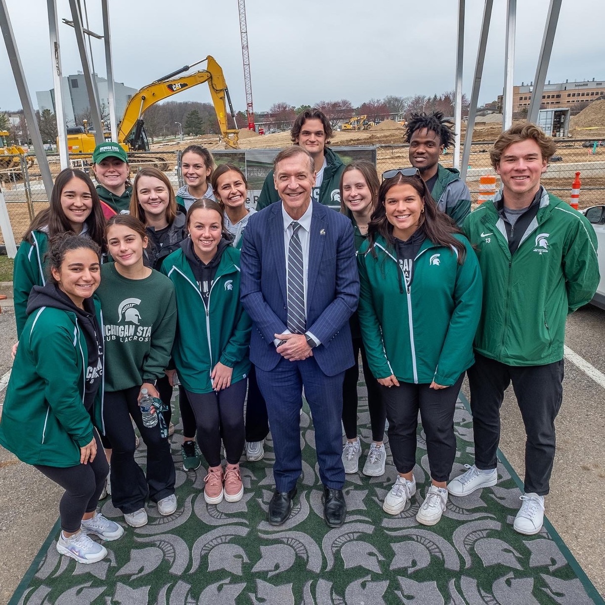 President Stanley with club sports and intramural sports students in front of construction site for the Service Road turf fields