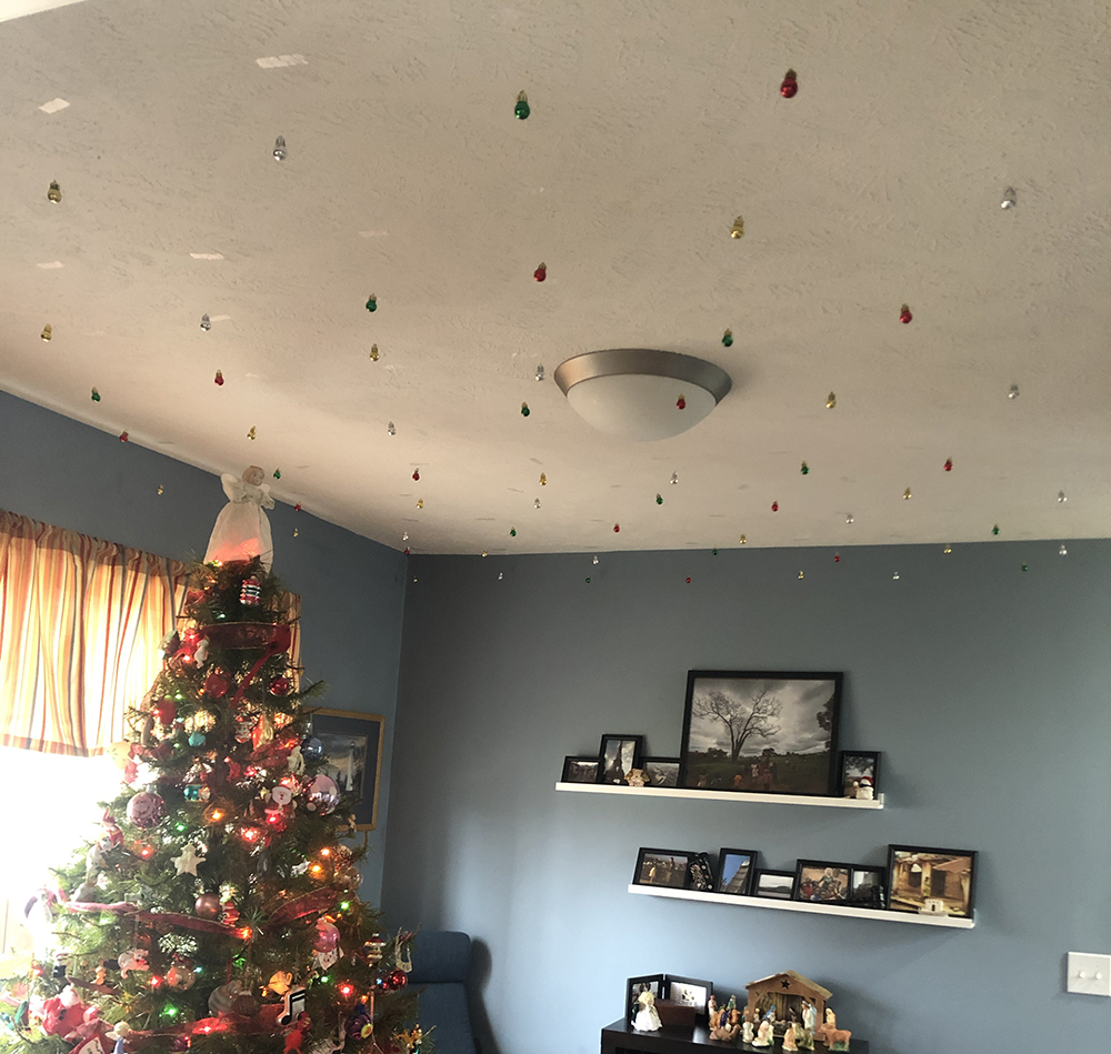 tiny ornaments hanging from the ceiling by a Christmas tree