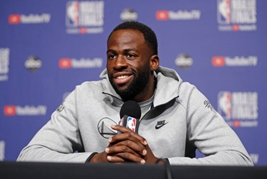 Draymond Green speaking into a microphone at an NBA press conference