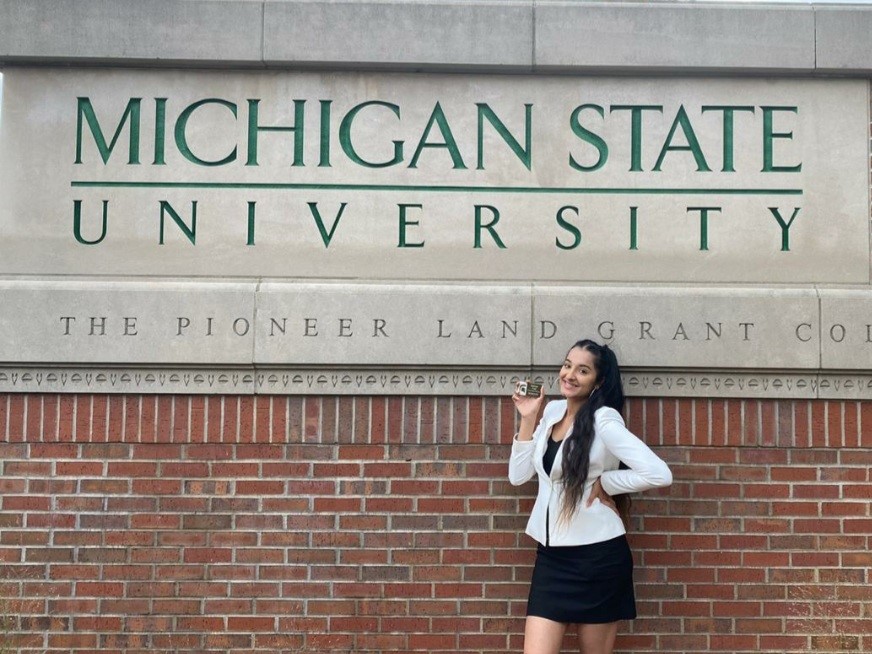 Simone Nagi standing in front of the MSU sign