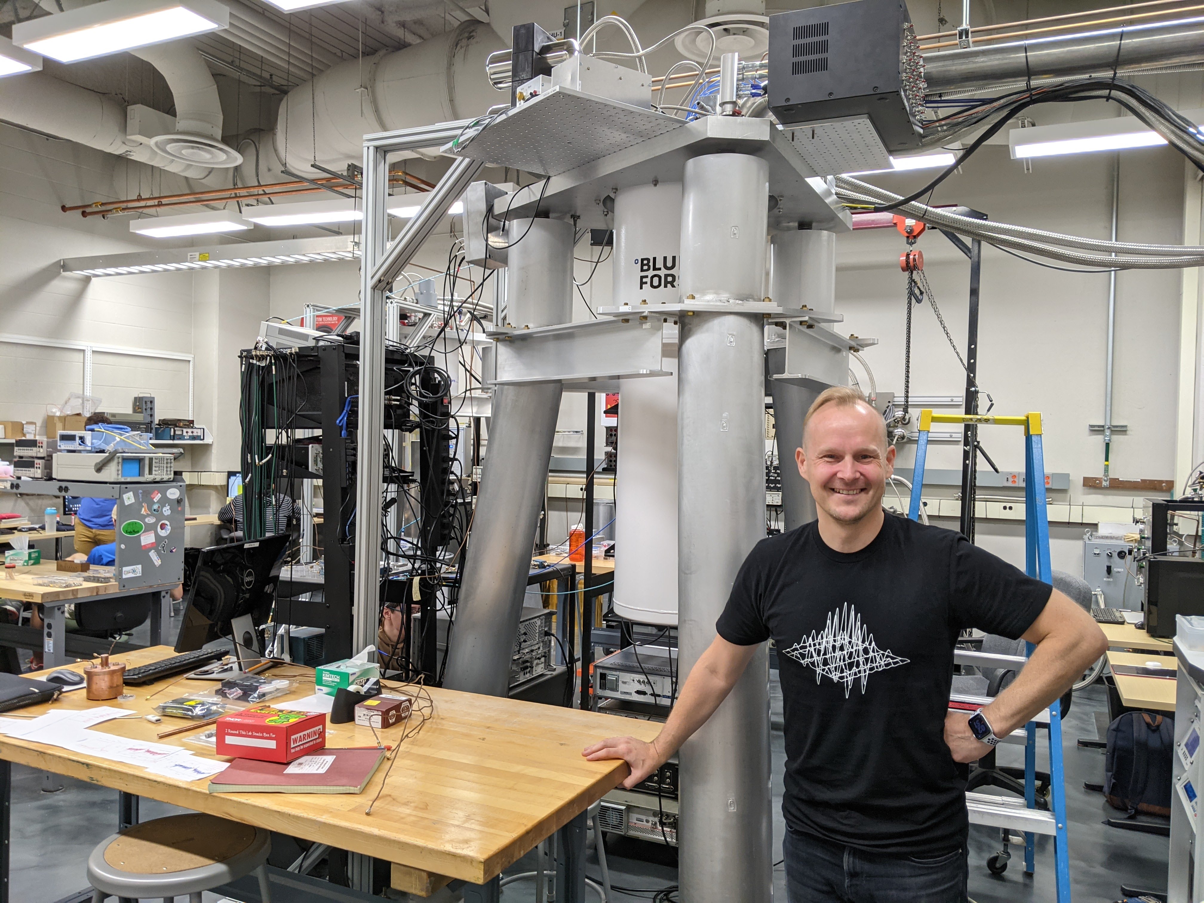 Jerry Cowen Endowed Chair of Experimental Physics Johannes Pollanen in his quantum physics workshop with metal machinery and racks of electronic devices.