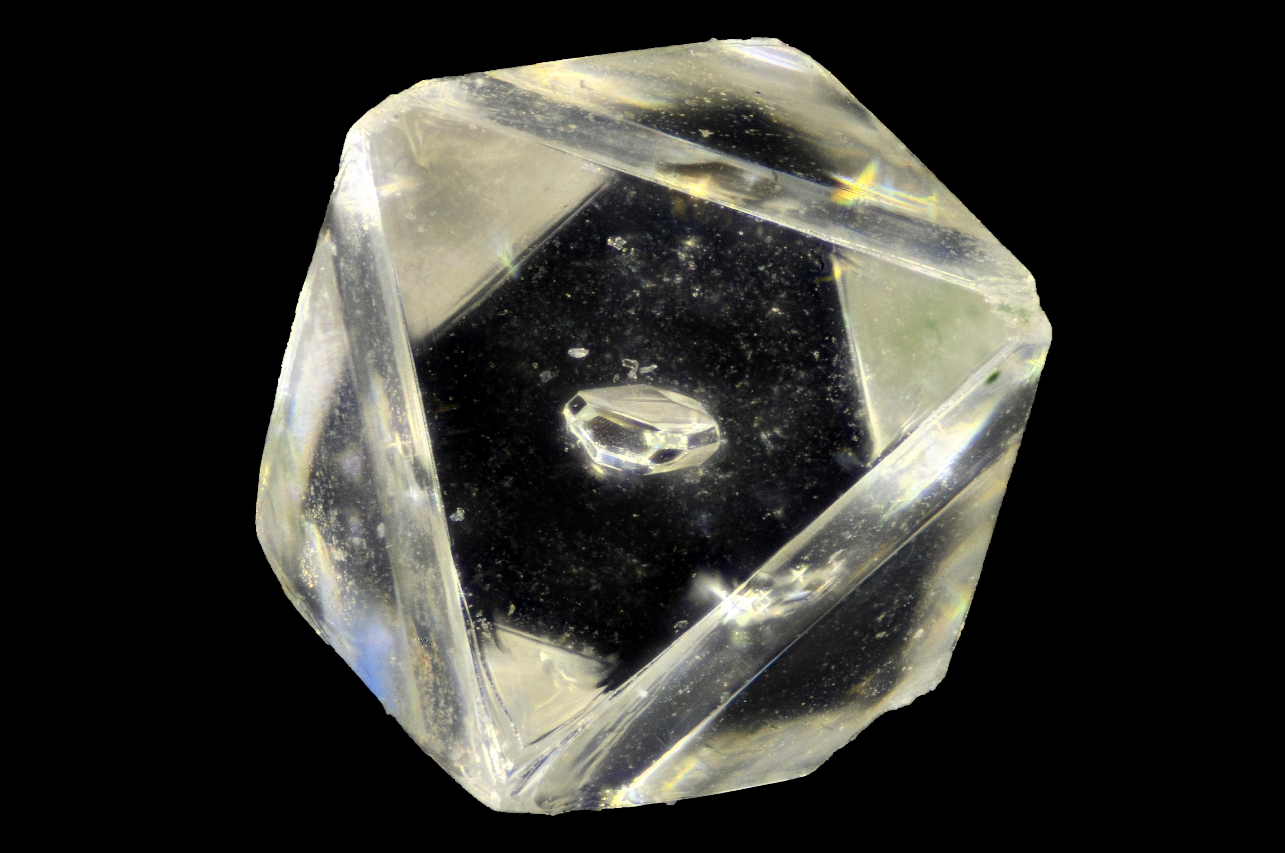 A clear diamond with a speck in the middle — called an inclusion — sits against a black background.