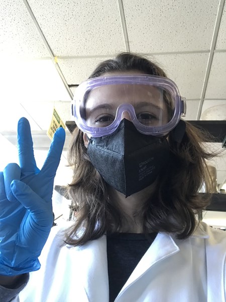 Alexandra Korabiewski in a lab coat, mask, goggles and gloves
