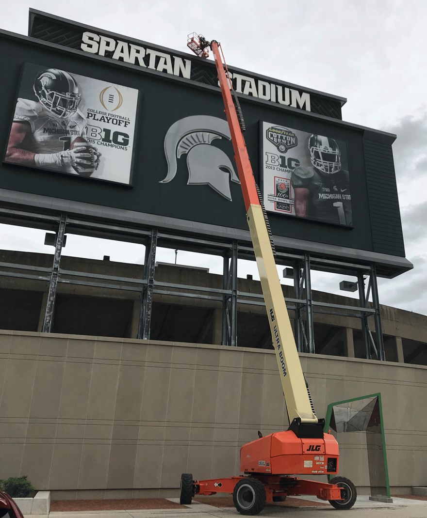 IPF electrician Brian Lewis uses a 150-foot lift to replace an exhaust fan on the Spartan Stadium scoreboard.