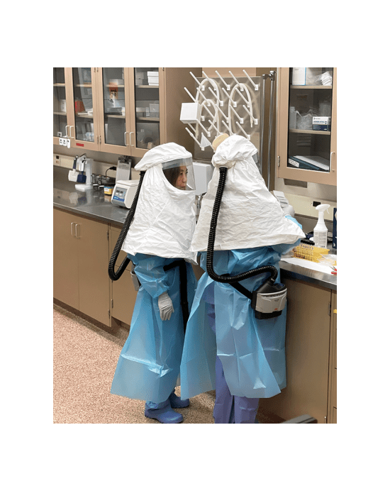 Wise and Thompson handle samples to prepare for testing. Note that both are wearing powered air-purifying respirators and other personal protective equipment, including shoes, that are only used in this space and will be thoroughly disinfected following completion of testing.