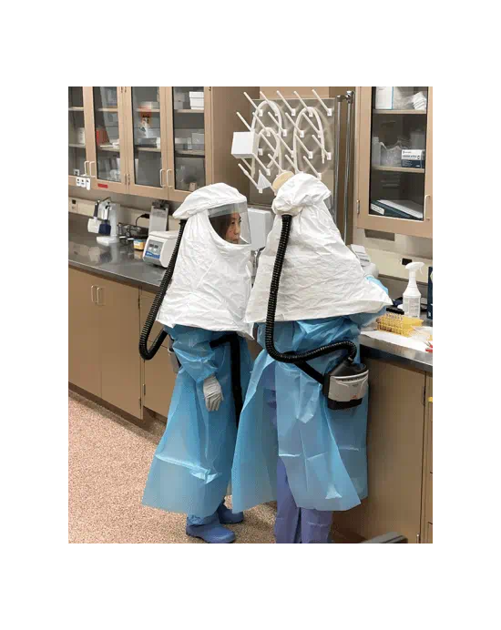 Wise and Thompson handle samples to prepare for testing. Note that both are wearing powered air-purifying respirators and other personal protective equipment, including shoes, that are only used in this space and will be thoroughly disinfected following completion of testing.