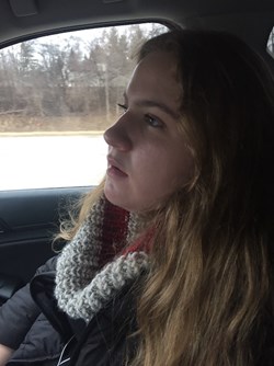 Anna Forest sitting in the passenger seat of a vehicle wearing a scarf