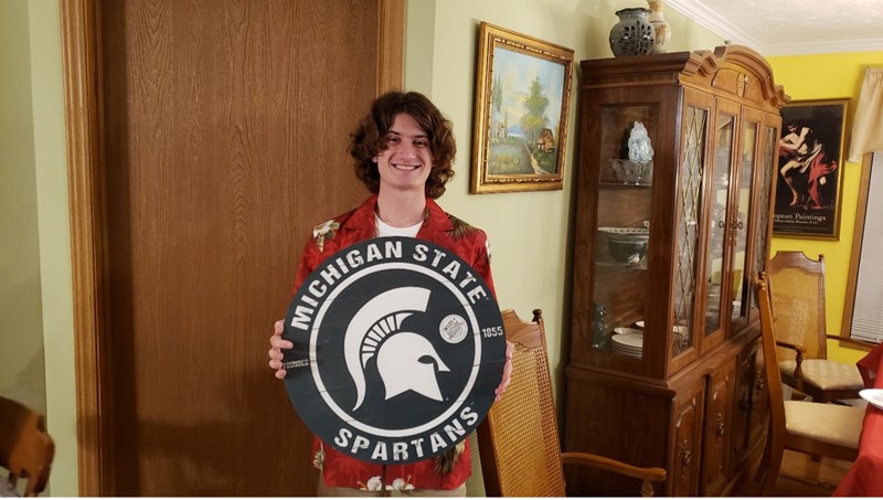 Ryan Peter holding Michigan State Spartans sign.