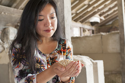 Felicia Wu holding a pile of corn kernels in both hands.