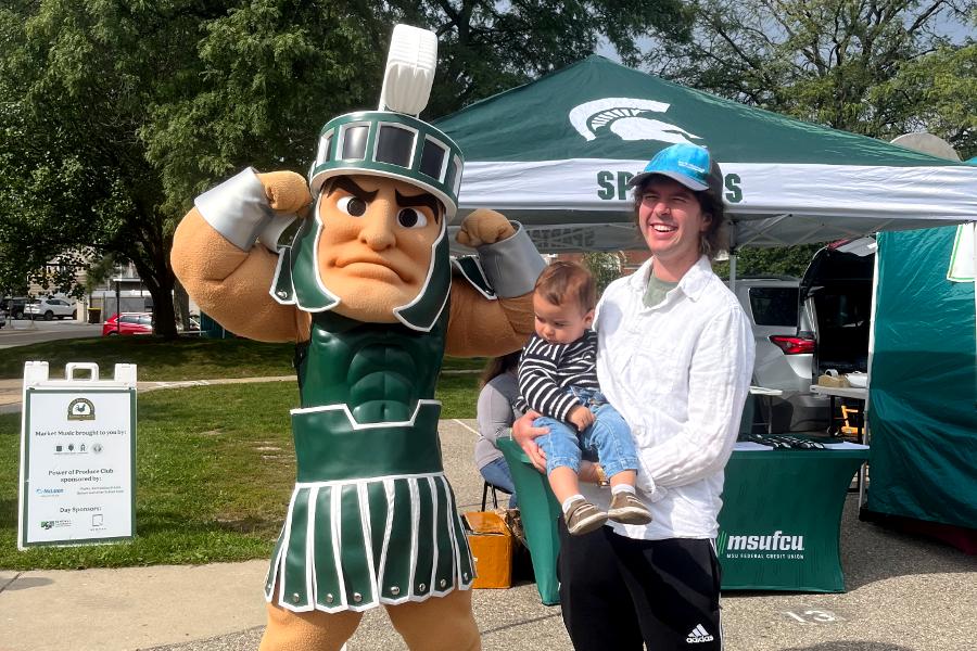 Elan Pochedley and his son with Sparty at the East Lansing Farmers Market. (Photo by Caroline Doenmez)
