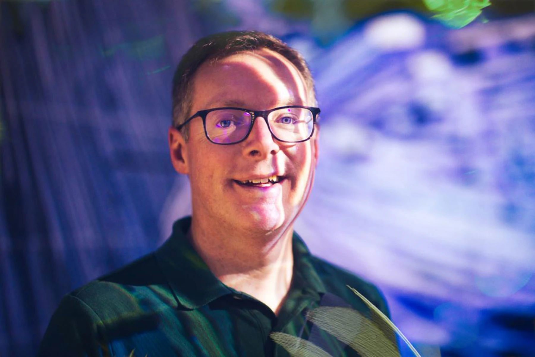 MSU Associate Dean and Professor Bill Hart-Davidson in front of a background of projected and shifting blue light.