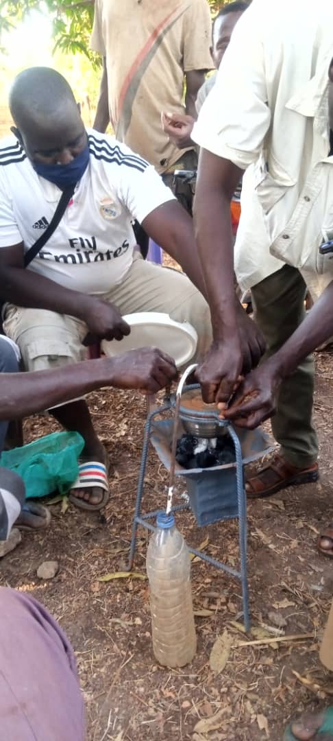Artisanal gold miners work with a retort constructed out of metal. It’s a little covered crucible that stands on three legs and has a lid. A tube on top of the retort is angled into a water bottle sitting on the ground.
