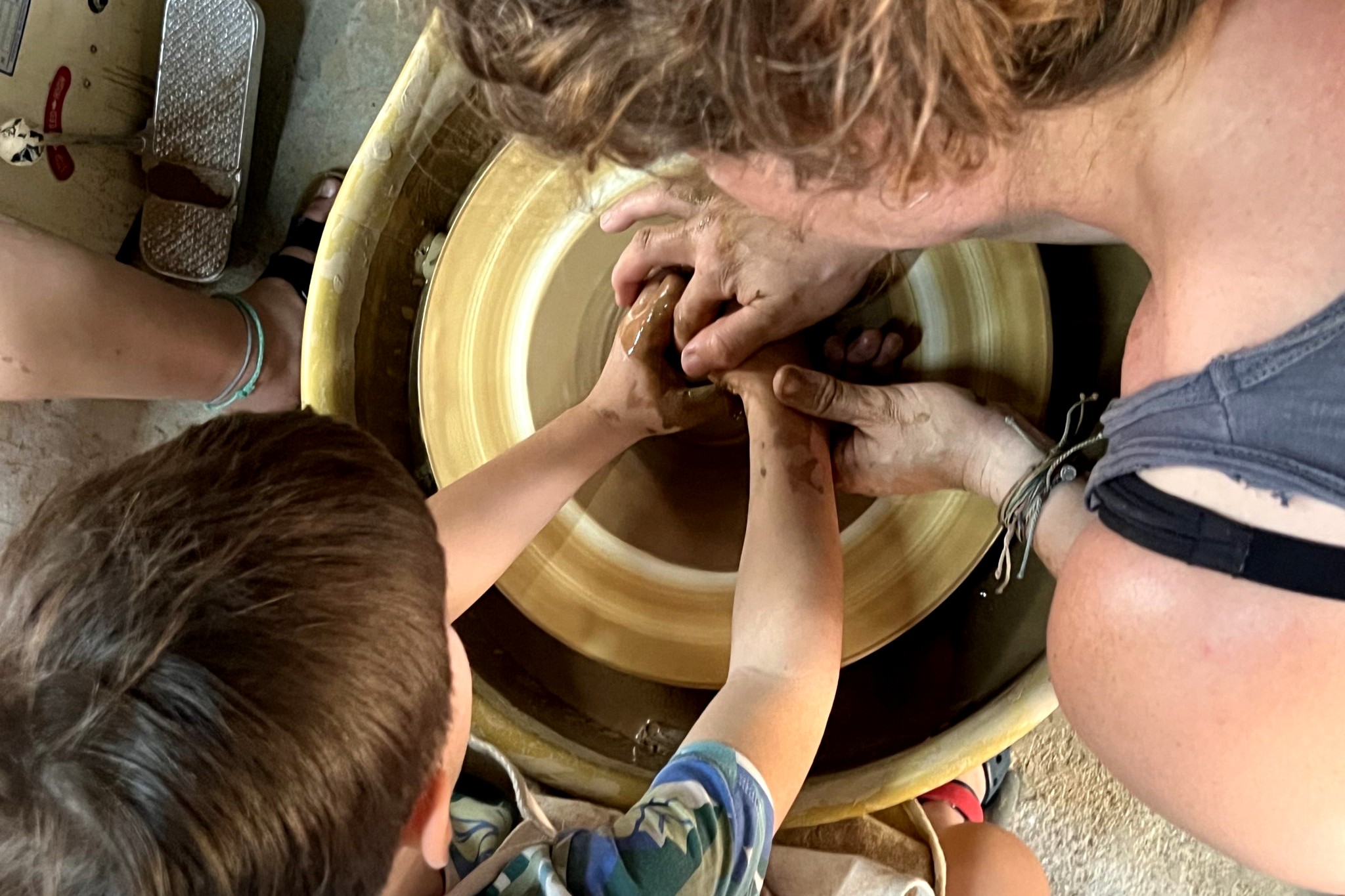 Assistant Professor Rebecca Casement (right) teaching a Greek child how to use a potter’s wheel at the Global Arts Studio in Corinth, Greece, where students in the Ceramic Arts in Greece Study Abroad created their own pieces of art.