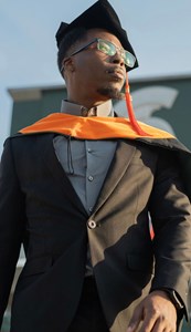 Jamell Dacon wearing a cap and gown in front of the Spartan Stadium.