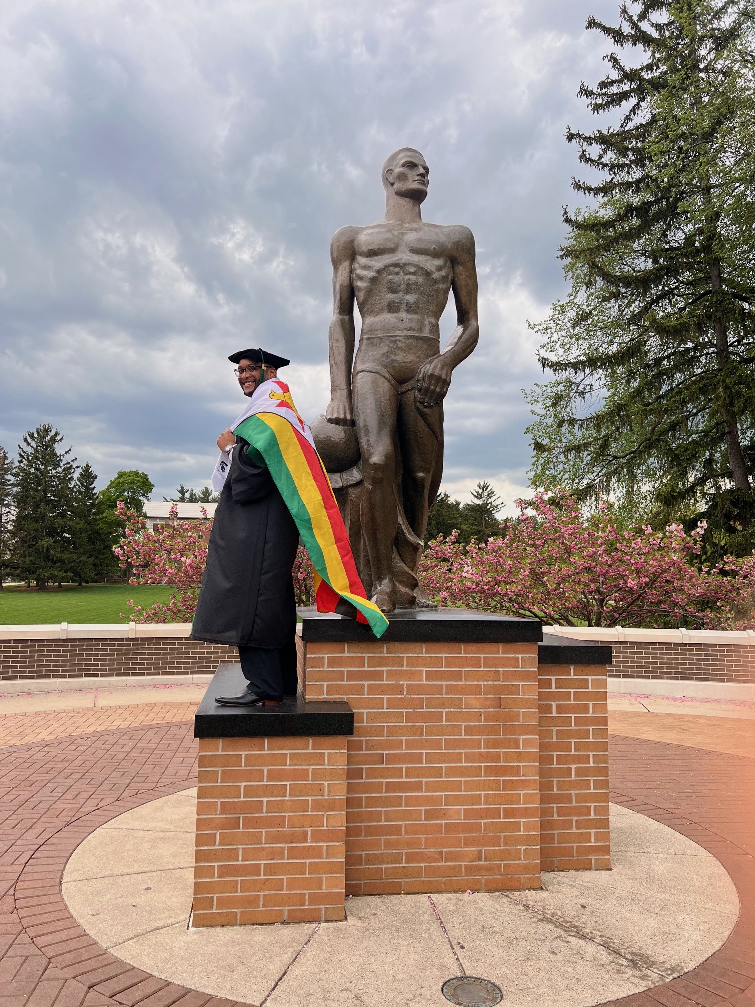 Andrew Michael poses in front of The Spartan statue with the flag of Zimbabwe draped around his neck. 