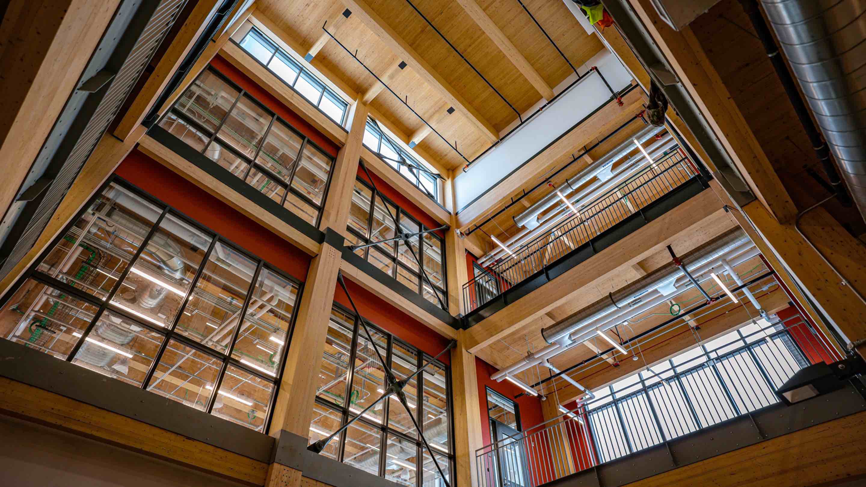 A photograph of the inside of the STEM Teaching and Learning Facility shows exposed mass timber, steel supports and windows. 