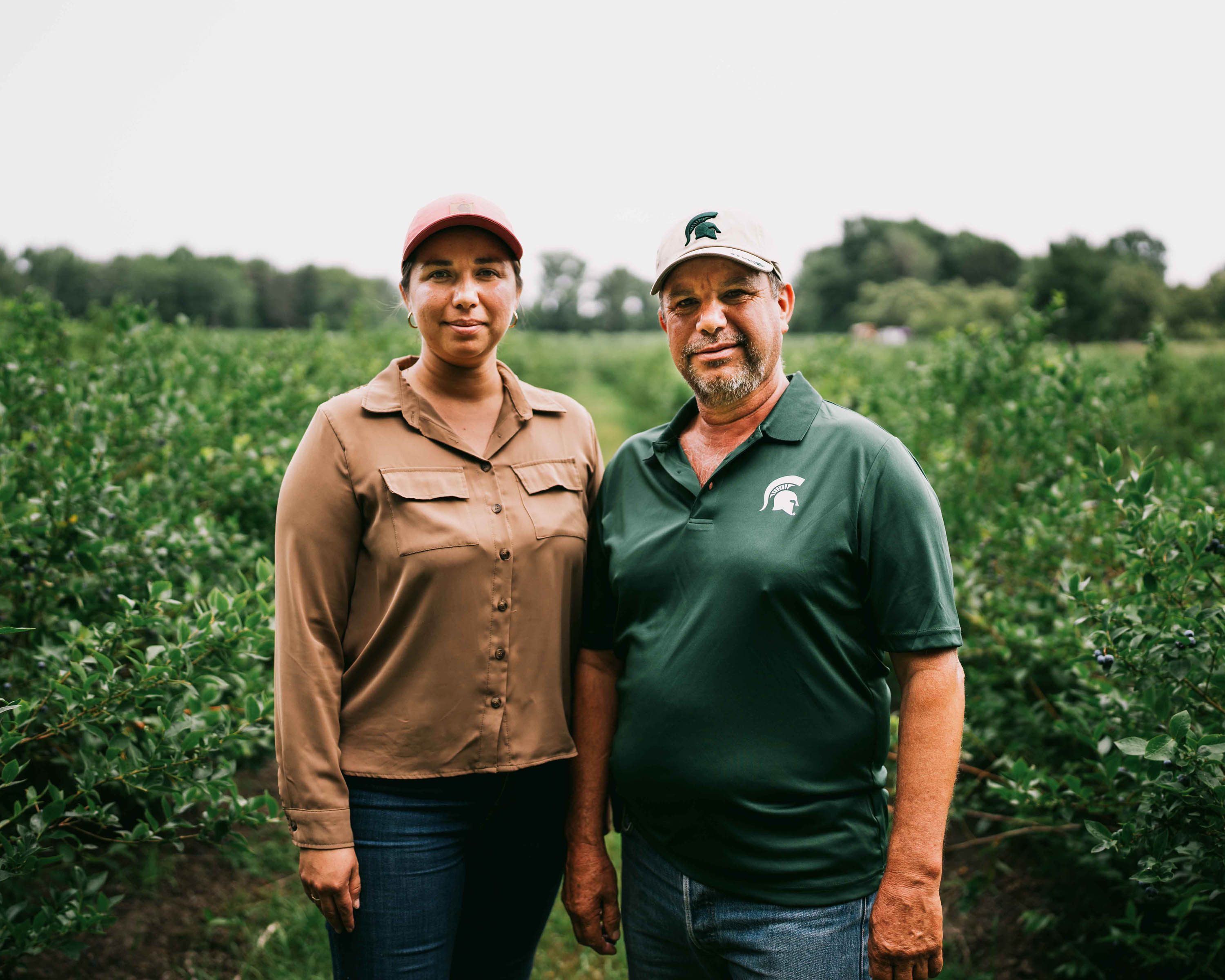 Juan Pedro and his daughter standing in front of rows of blueberries.