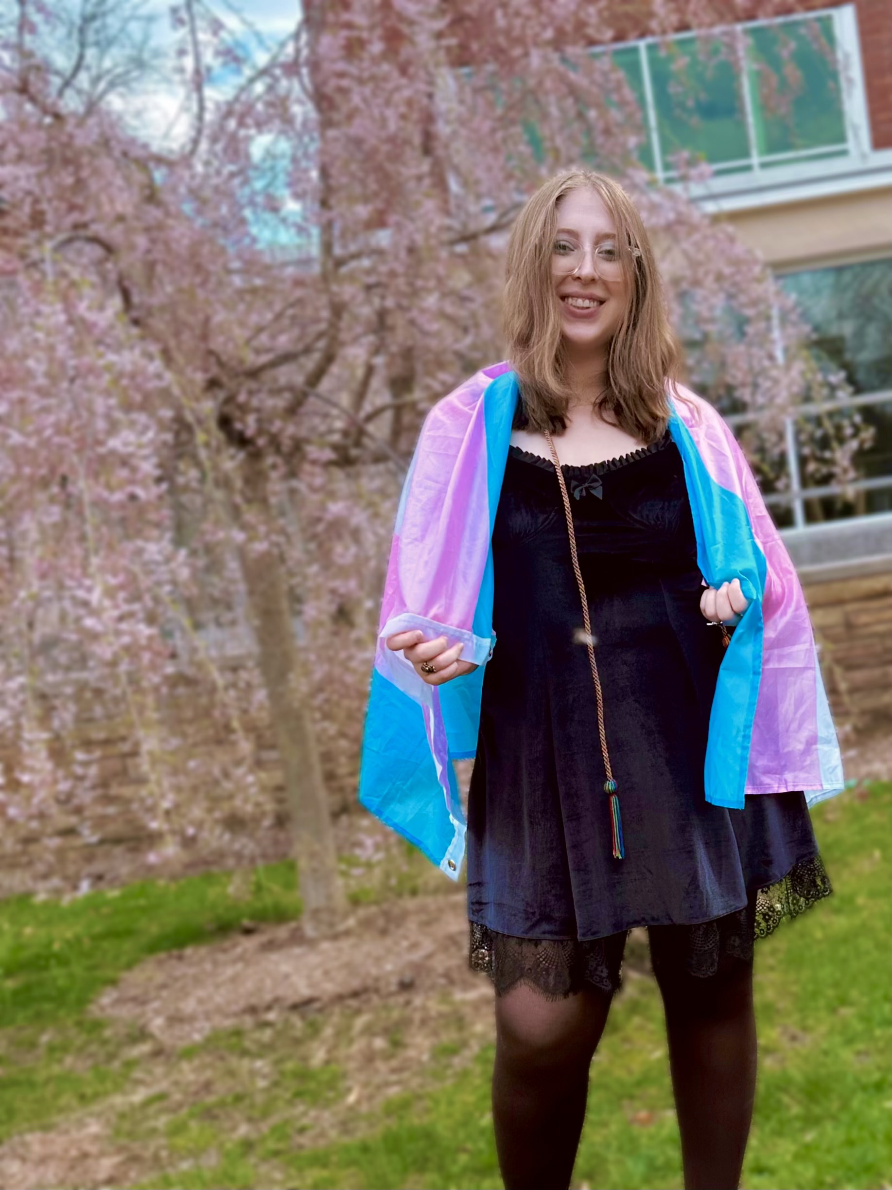 Angela Demas with a transgender flag draped across their shoulders