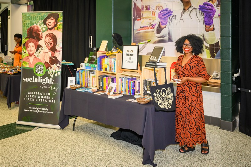 Vendor stands next to their display table at the 2022 Juneteenth Celebration