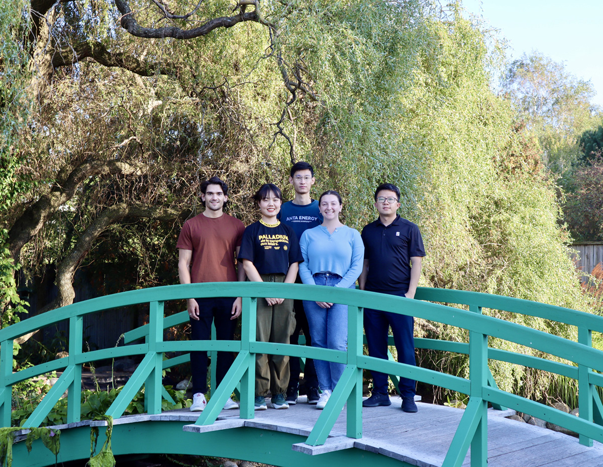Assistant Professor Jinxing Li of Michigan State and members of his research team stand on an arched bridge in front of trees. The team includes, from left to right, doctoral student Vittorio Mottini, doctoral student Yulu Cai, postdoctoral scholar Yi Xing and undergraduate research assistant Paulina Bies. 