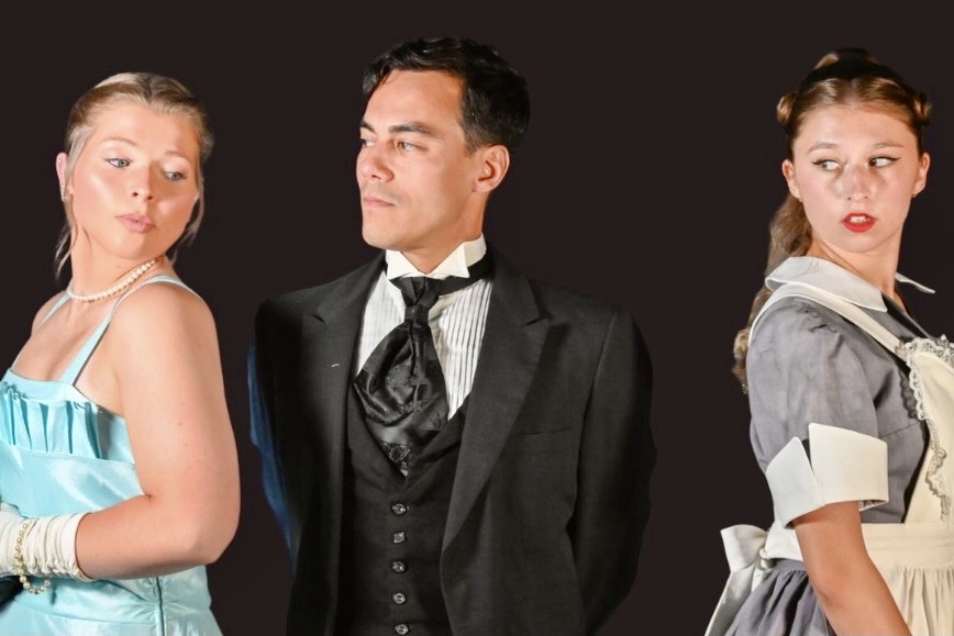 Three actors, from left to right, a woman dressed in a light blue dress with pearls on, a man in a tuxedo with an ascot, and a woman dressed in maid attire with a white apron, representing characters from the movie and game 