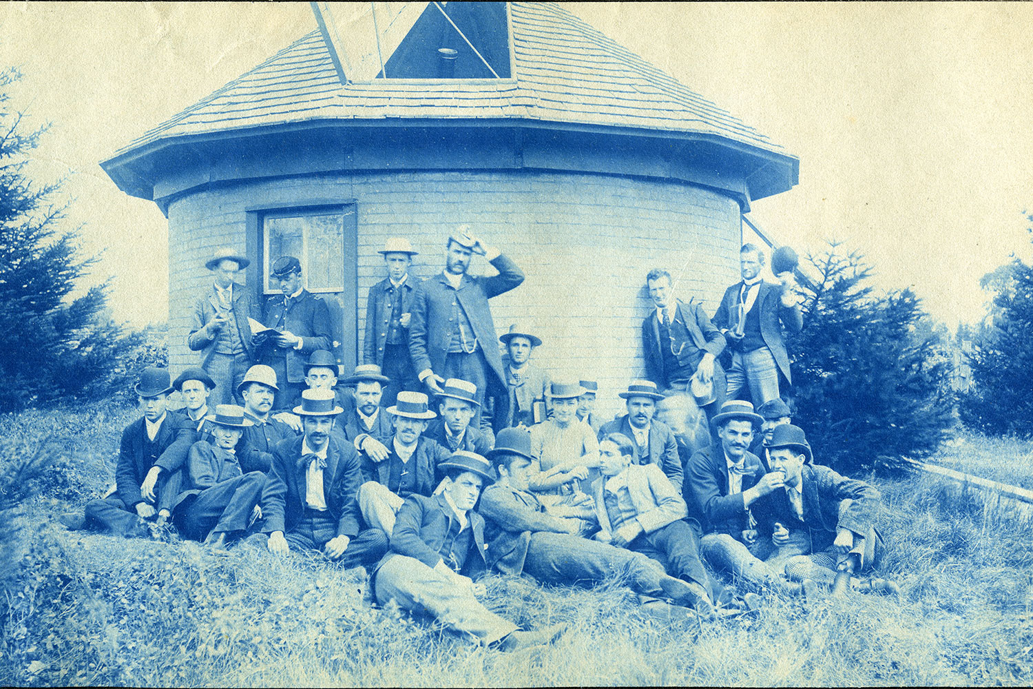 A black and white historical photo of men posing outside of MSU’s first observatory.