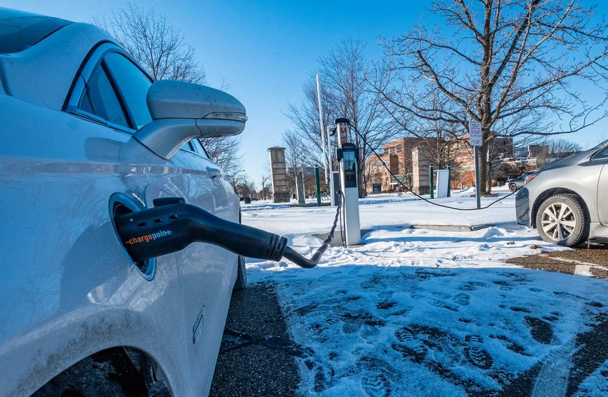 An electric vehicles charges in a snow-covered parking lot near the MSU International Center.