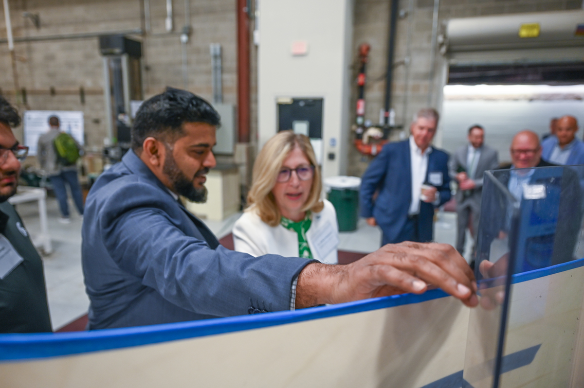 Mahmood Haq talks to Teresa Woodruff in front a poster presentation at the announcement of a new MSU mobility initiative with the U.S. Army.