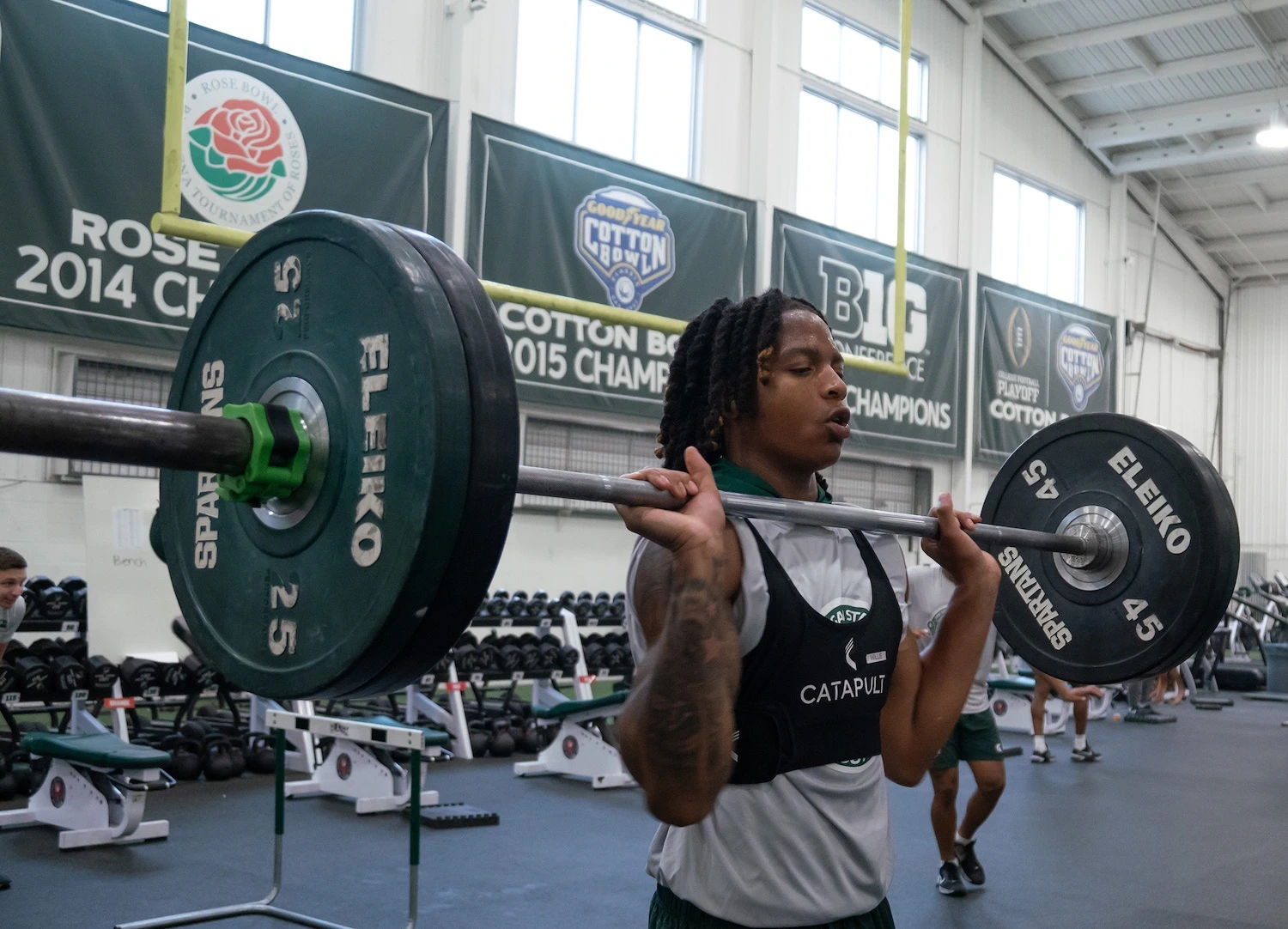 MSU football player Ade Willie lifts weights while training in the catapult tracking device