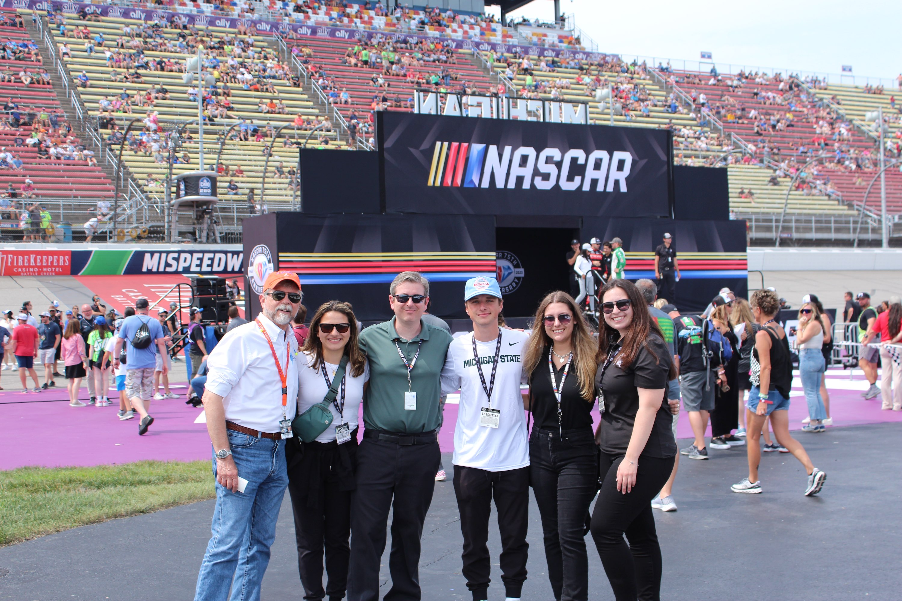 A group of MSU researchers pose at a NASCAR race, on the infield