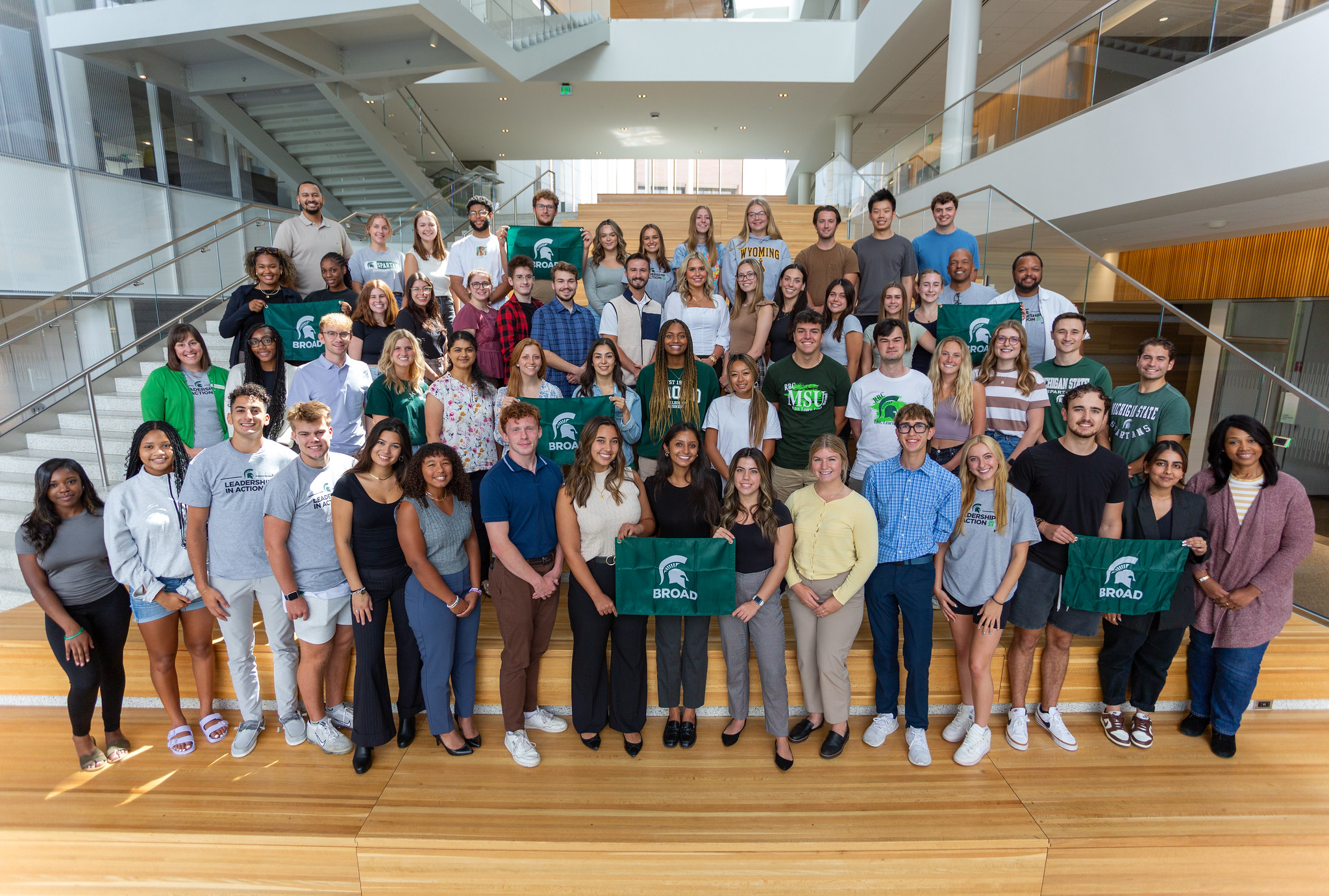 A large group of students pose on a staircase--some of them hold Spartan flags