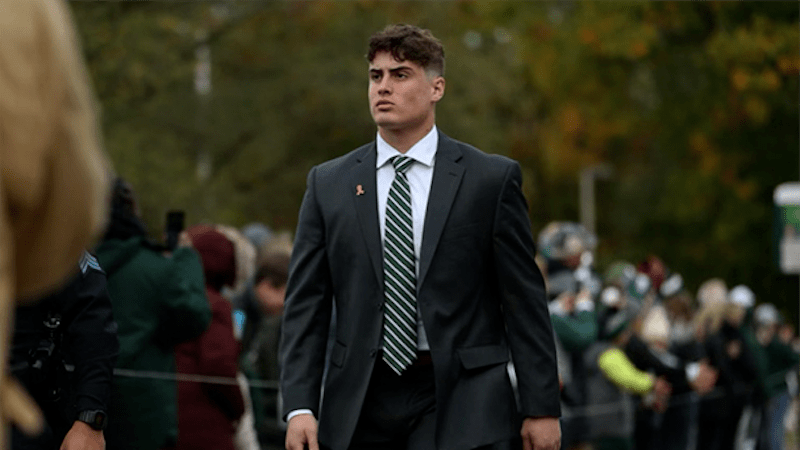MSU football player Sam Edwards walks in a suit and tie