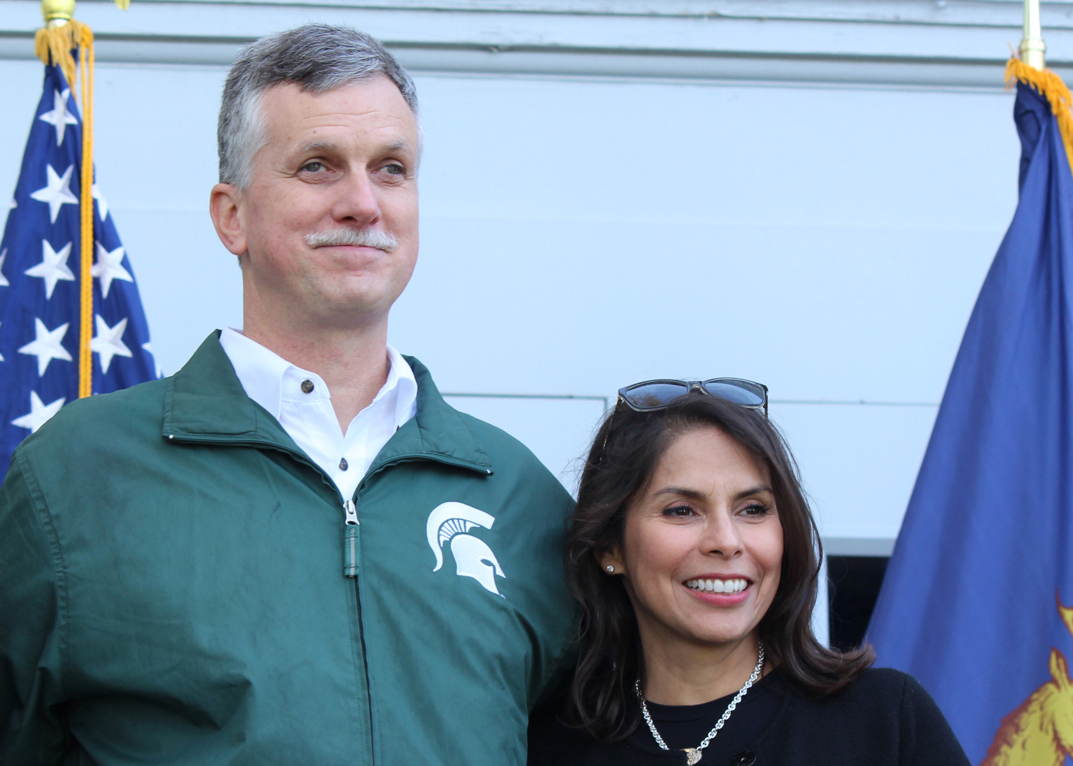 Michael Hudson and Julianna Powell pose between two flags.