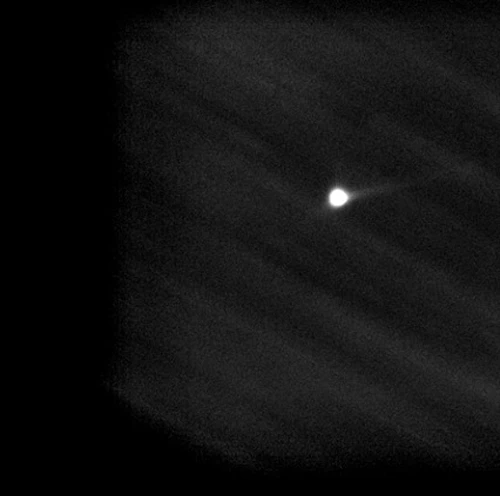 An image created by the telescope at the MSU Observatory showing the asteroid system struck by NASA’s Double Asteroid Redirection Test, or DART. The asteroids appear as a small, bright white circle standing out against the darkness of a night sky. A thin, faint white tail extends to the right from the circle, showing material ejected from one of the asteroids after being struck by the DART spacecraft.  