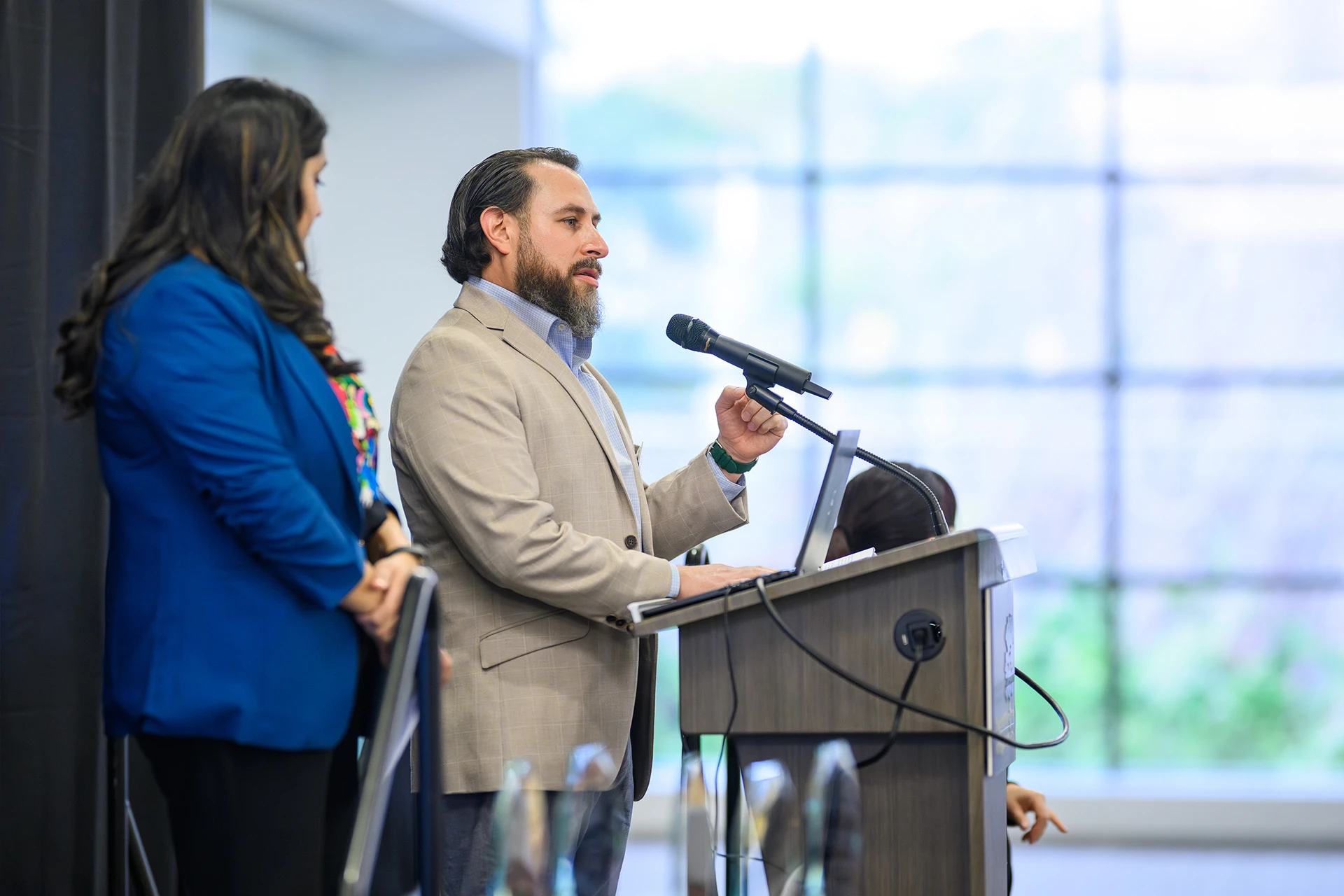 Elias Lopez speaking at the lectern with co-chair Amanda Flores looking on