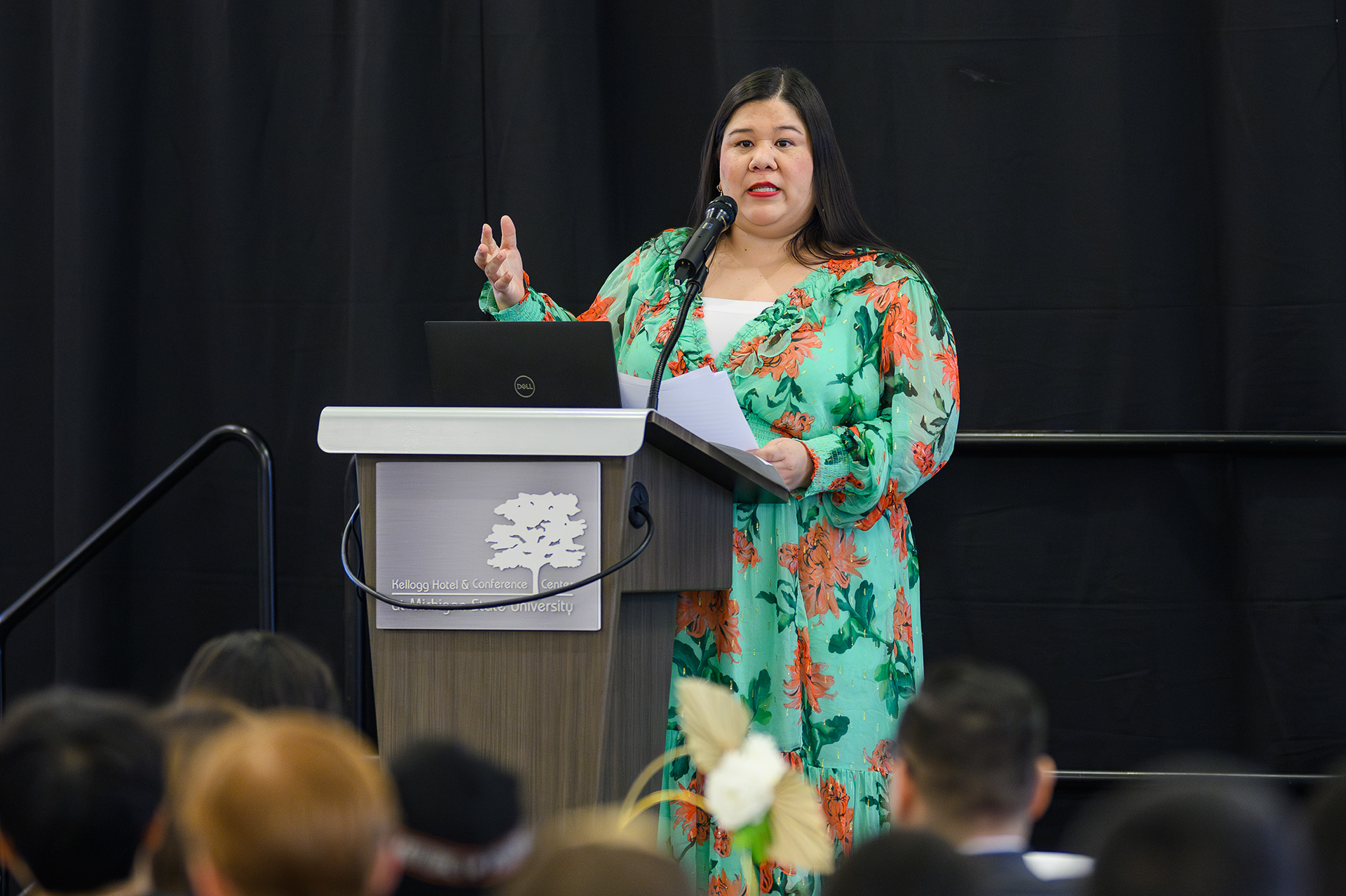 Keynote speaker Monica Ramirez speaks at the lectern wearing a colorful green dress
