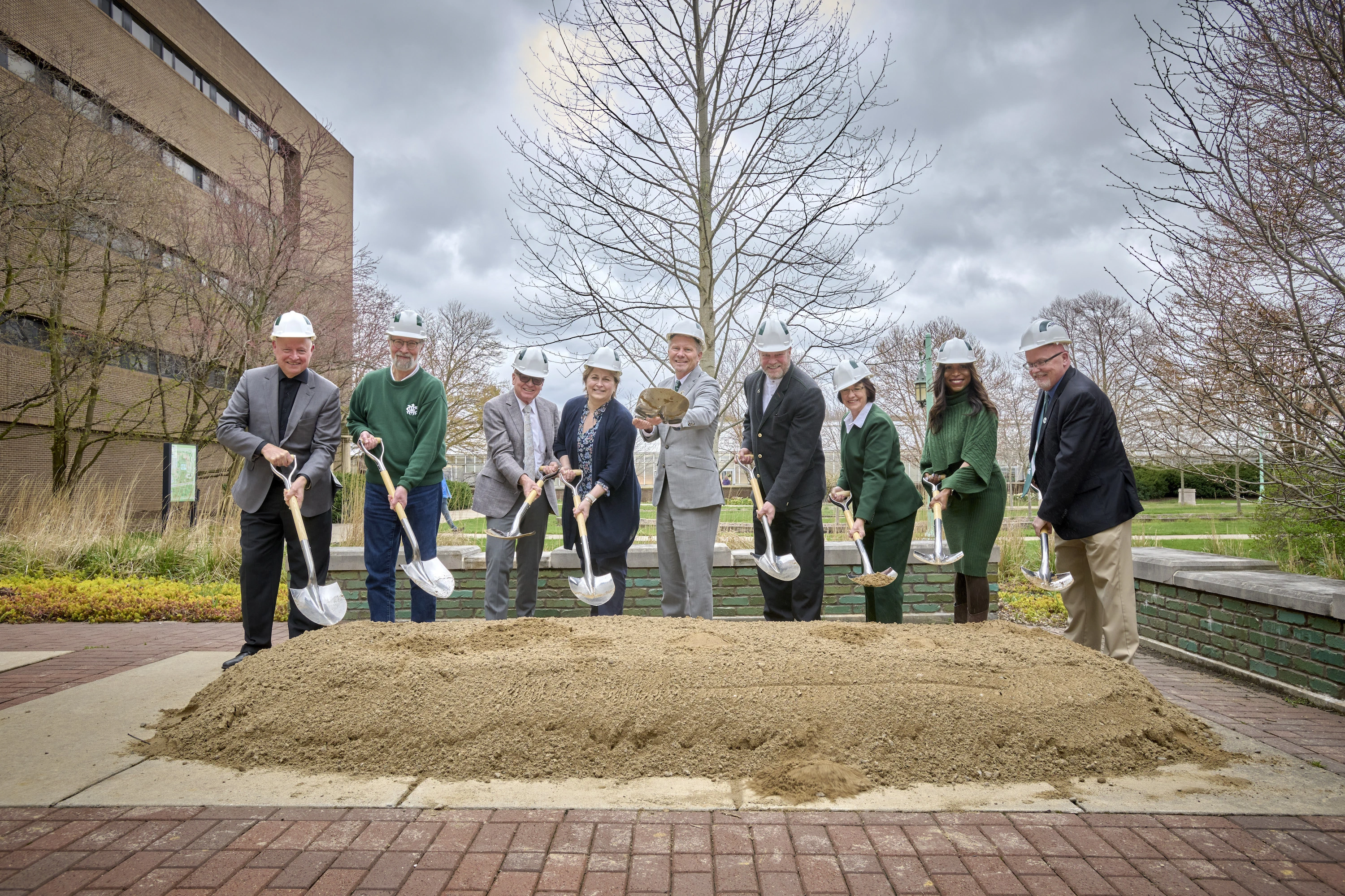 MSU leaders pose with shoves in front of a pile of dirt at a groundbreaking ceremony.