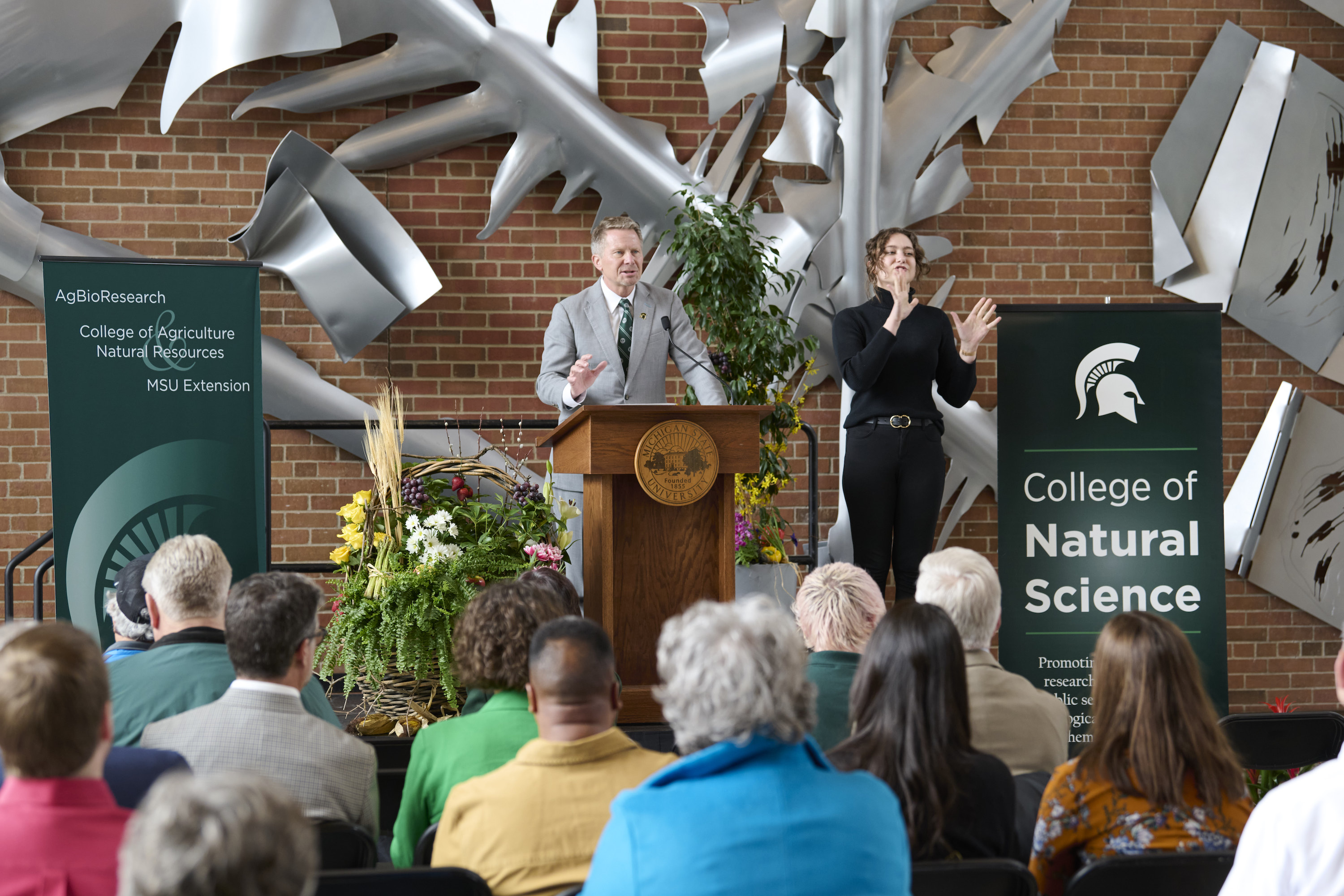 President Kevin Guskiewicz speaks at a podium during the Plant Science Greenhouses groundbreaking event. 