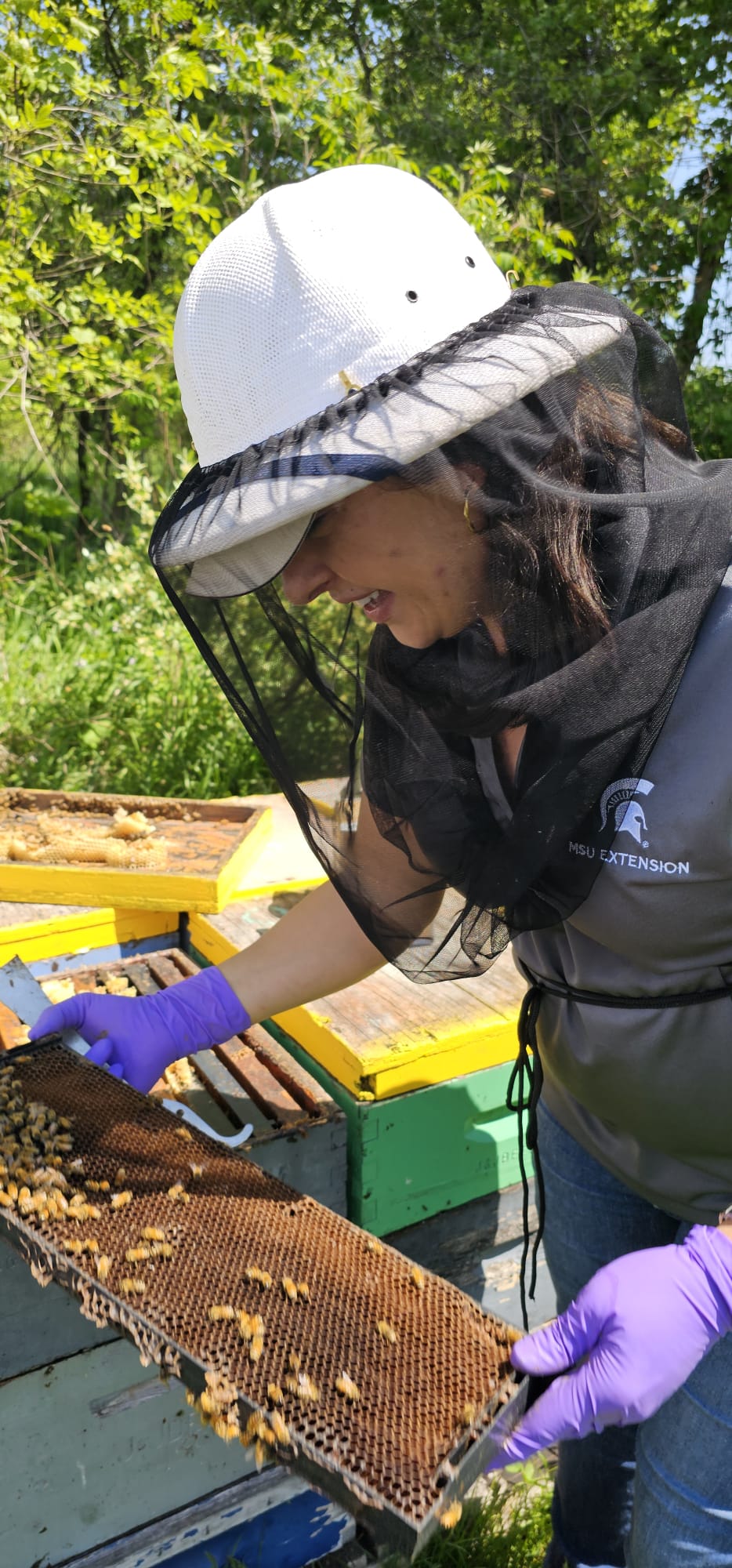 Anna Heck providing a bee keeper workshop, wearing netted protection and handling a honey comb