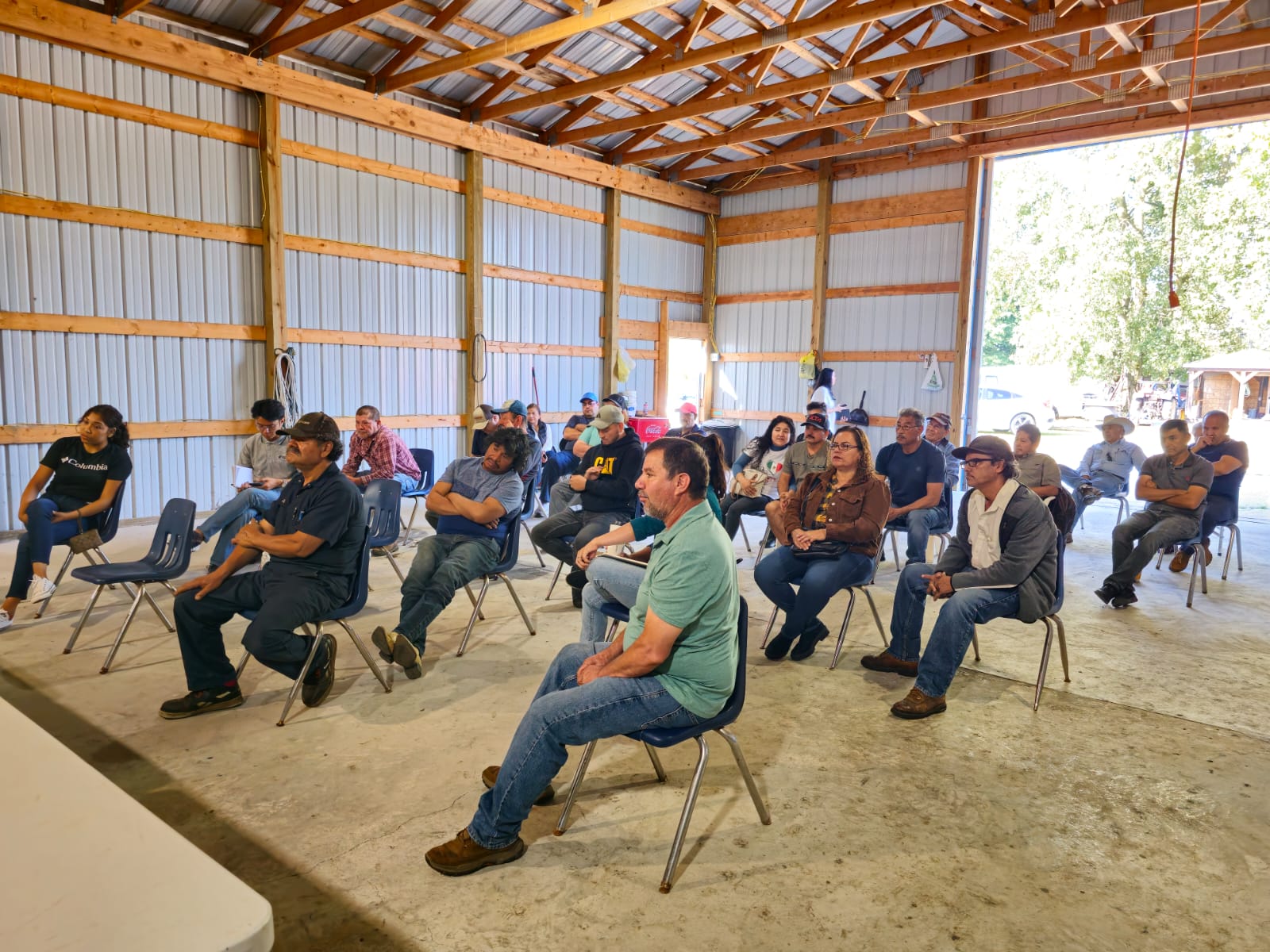 a group of attendees sit in chairs at a workshop in a barn
