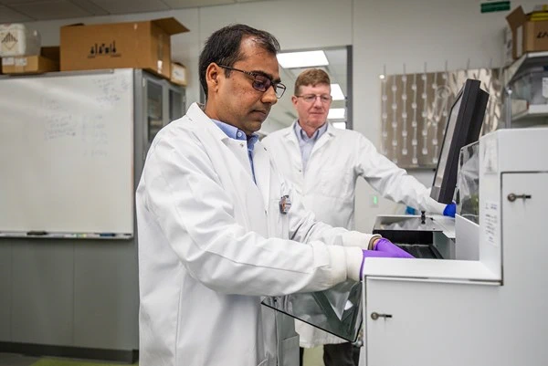 Dr. Satyendra Kumar Singh (left), measures radioactivity with a gamma counter, under the guidance of Dr. Kurt Zinn. (photo: Gary Caldwell Productions)
