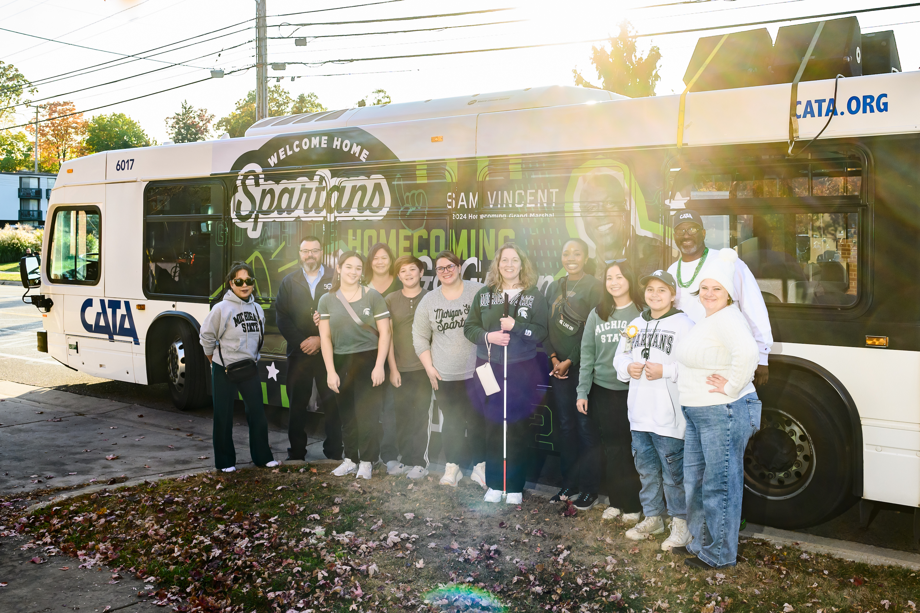 Individuals stand in front of a wrapped CATA bus that promotes the Homecoming parade.