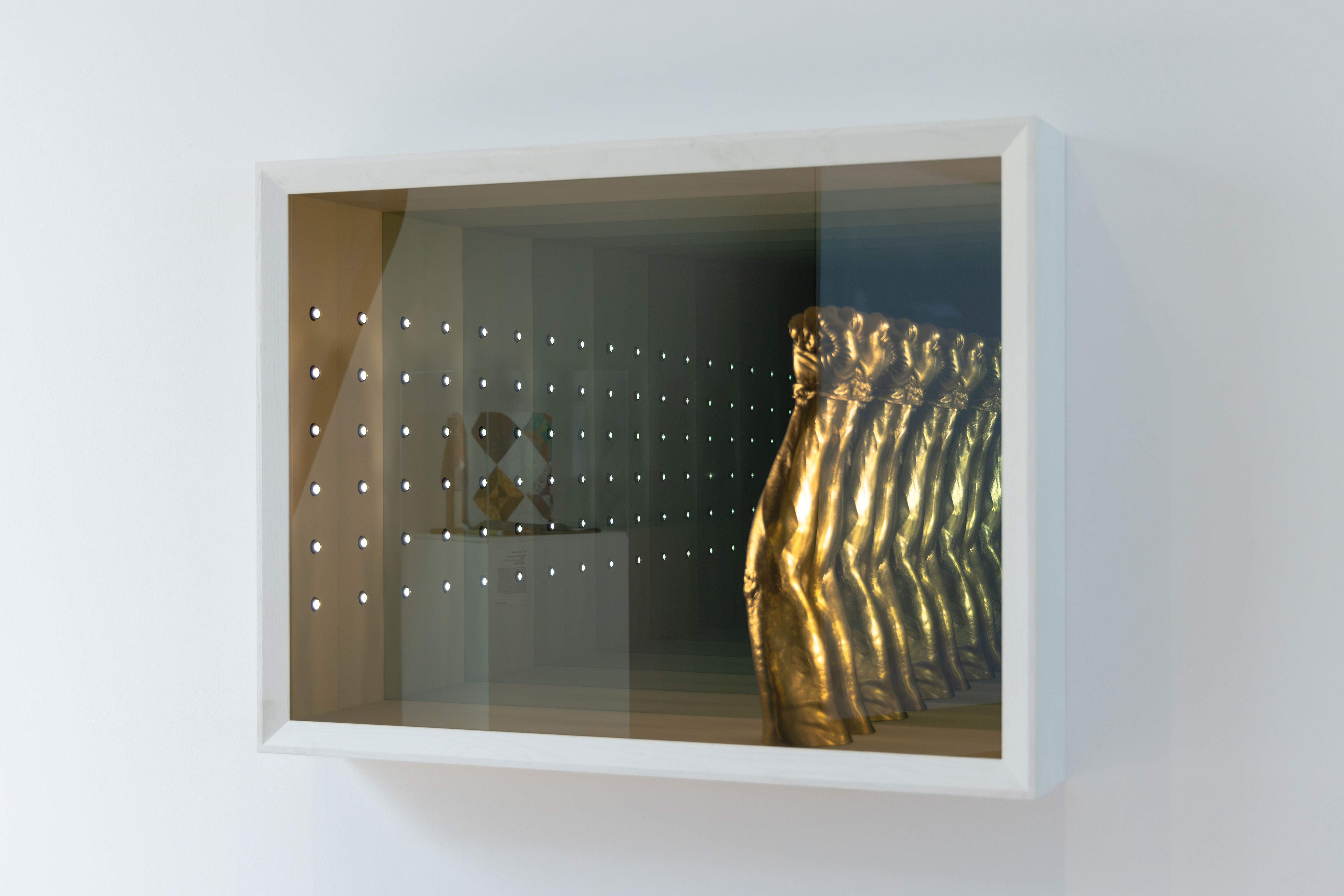 A gold cast of a fist in a frame of infinity mirrors. 