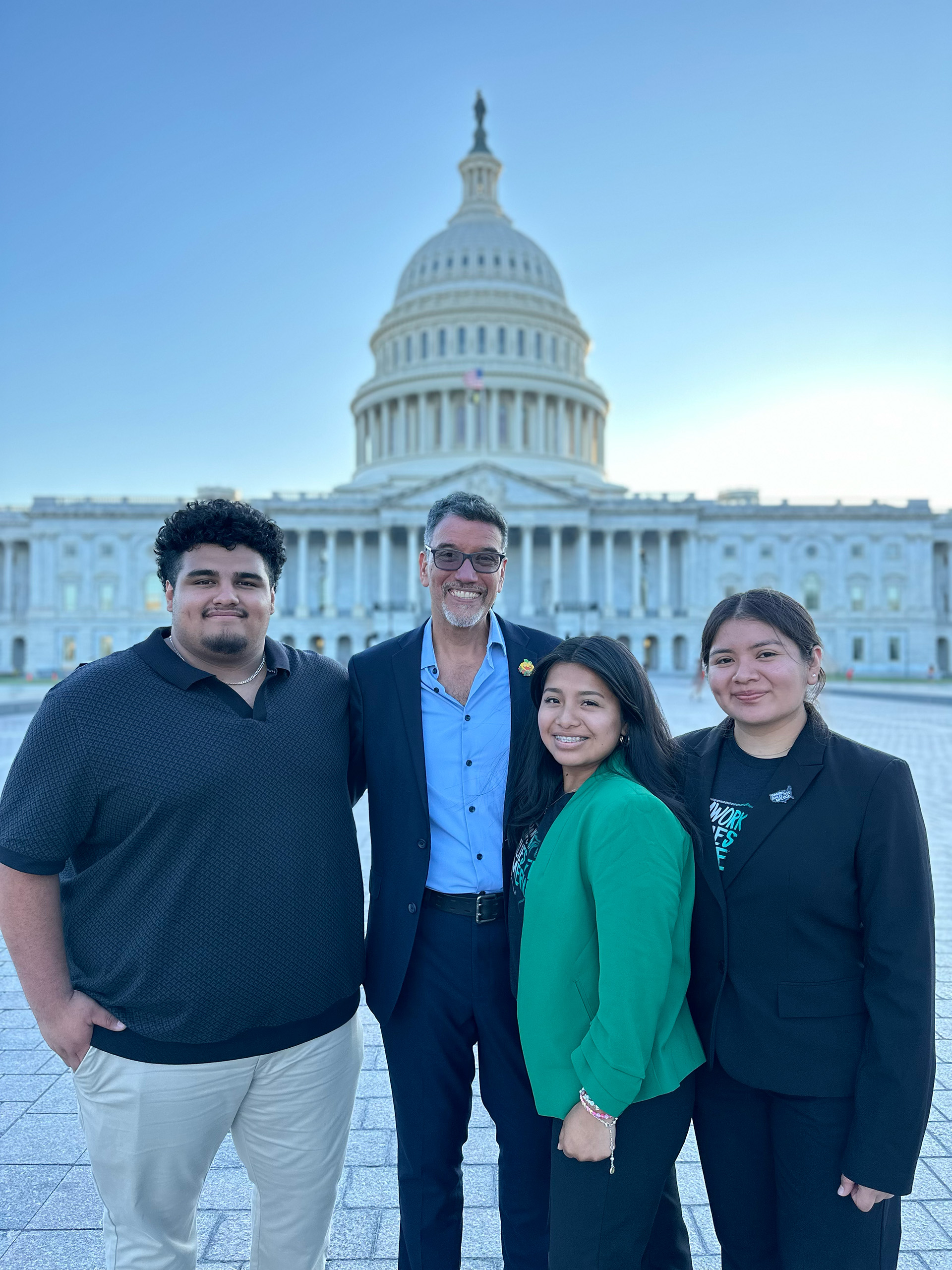 Three interns standing with advisor in front of Capitol Hill