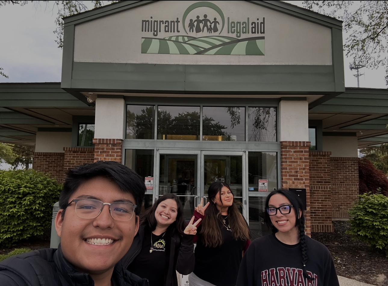 Group of four students taking a selfie in front of the migrant legal aid office