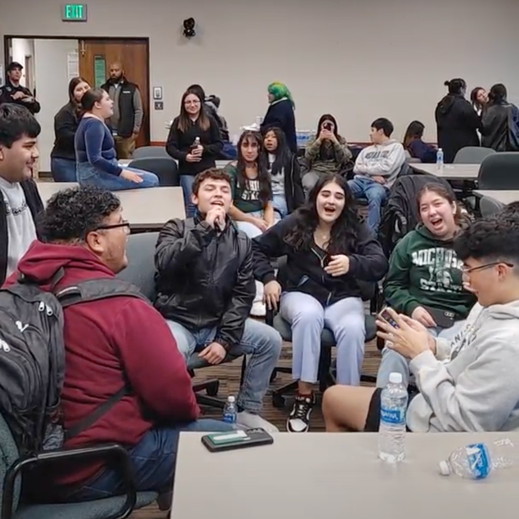 students sing karaoke while sitting and holding a microphone and laughing