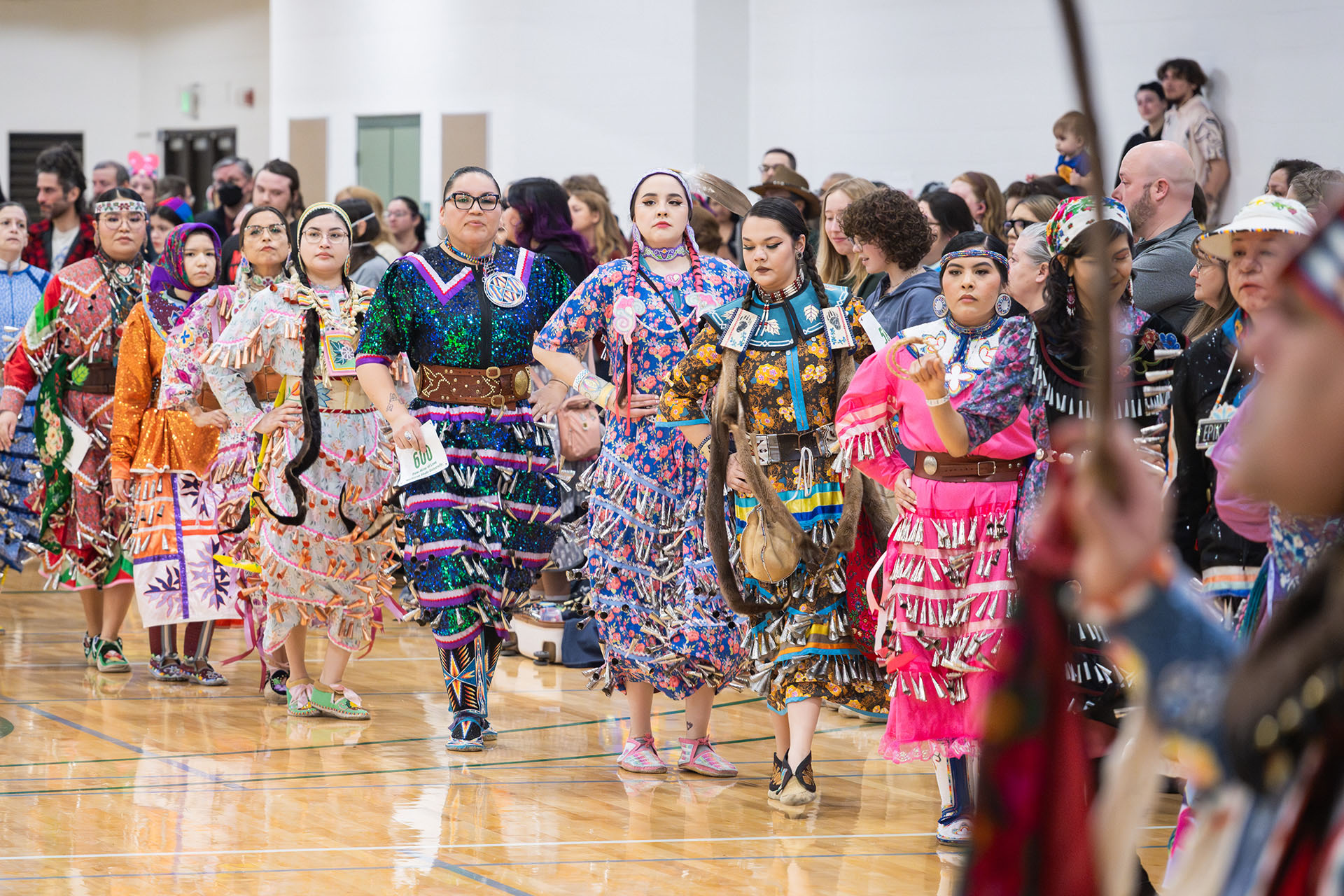 Powwow women dancers stand in a line