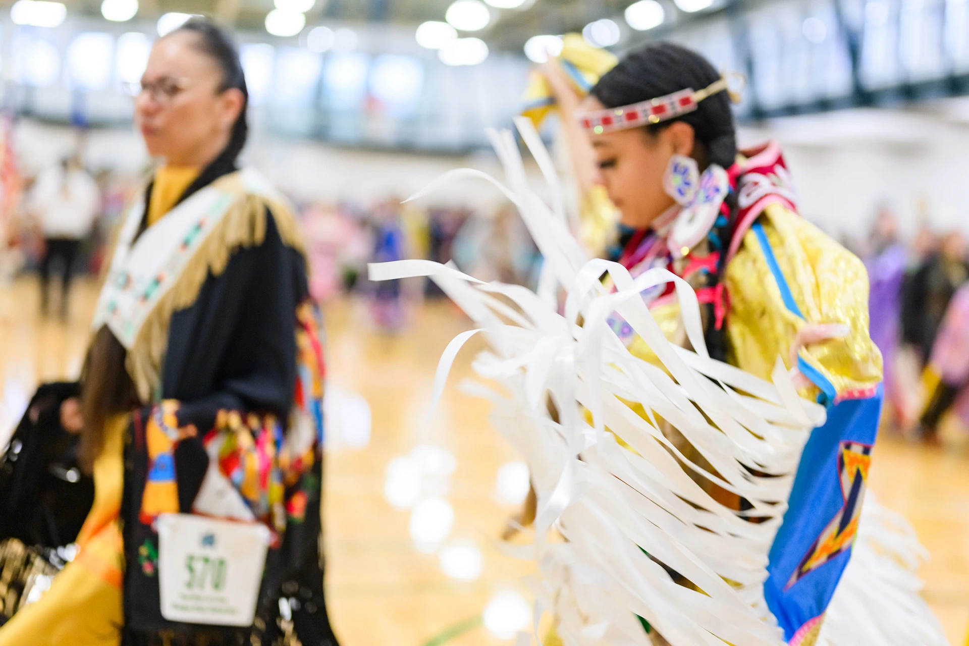 Powwow dancer's dress with white ribbons flow around her