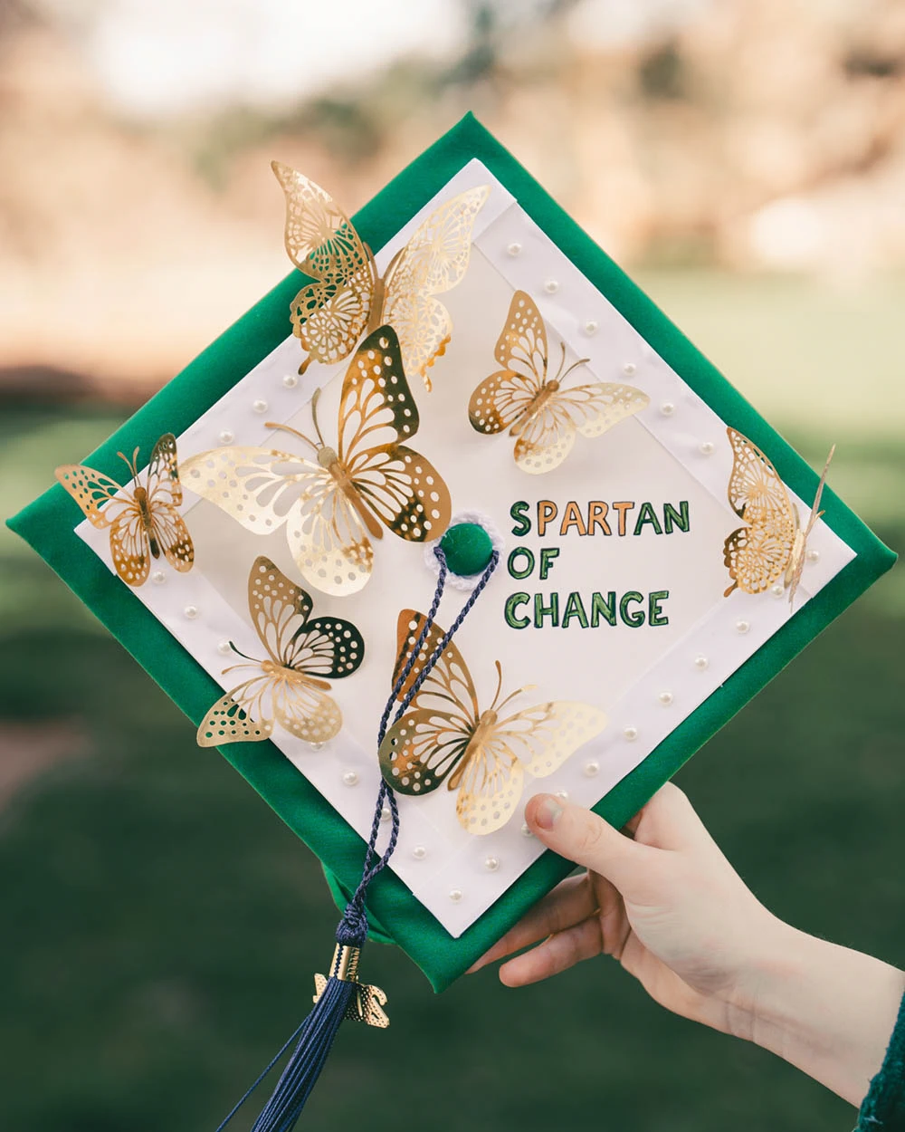 Graduation cap with text Spartan of Change and foil butterflies